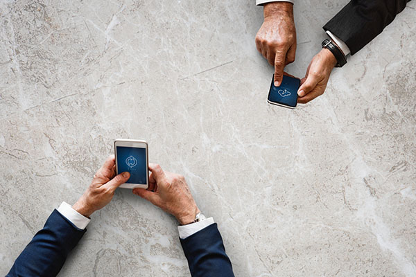 Zwei Geschäftsleute benutzen ihre mobile Geräte im Meetingraum